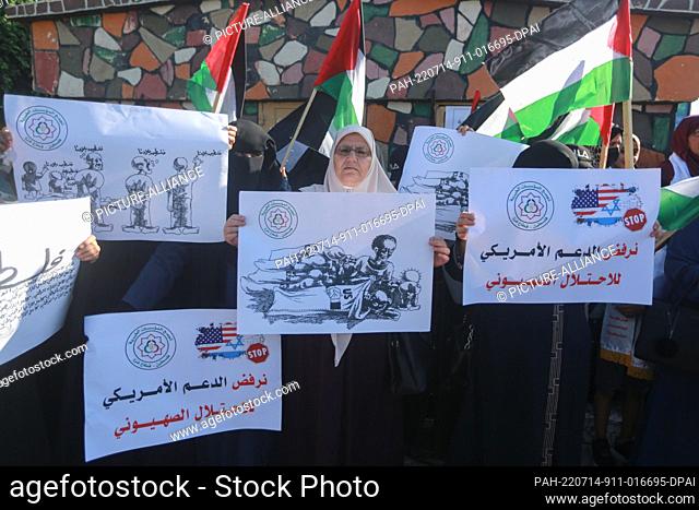 14 July 2022, Palestinian Territories, Gaza City: Palestinian women hold placards as they take part in a protest against US President Joe Biden's visit to the...