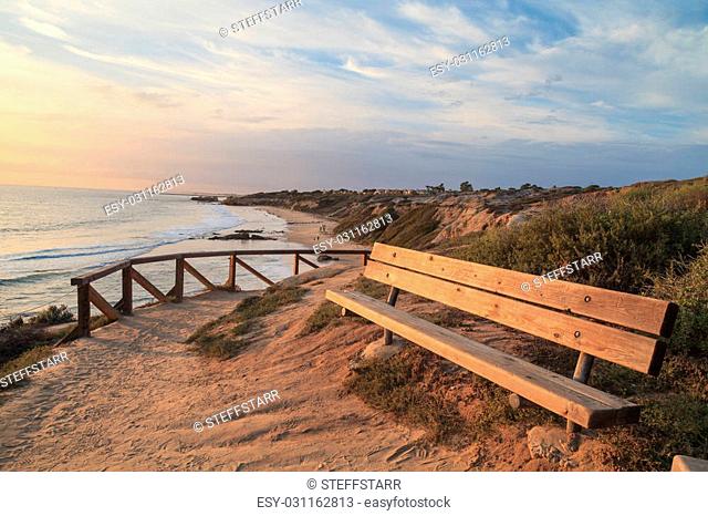 Bench at sunset along an outlook with a view of Crystal Cove Beach, Newport Beach and Laguna Beach line in Southern California