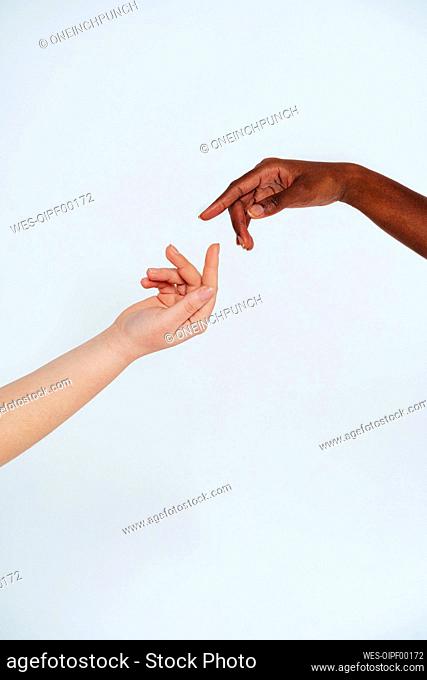 Women gesturing toward each other against white background