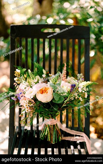 bridal bouquet of cream roses, pink peonies, eustoma, waxflower, astilbe, limonium, branches of eucalypt tree, mattiola, asparagus with cream ribbons on the...