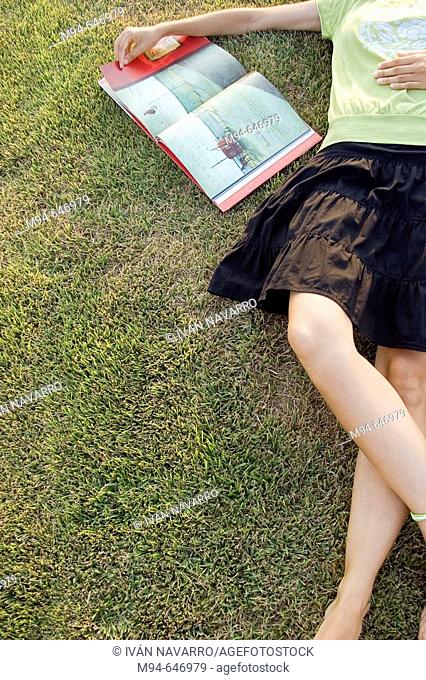 Woman laying on grass reading a book