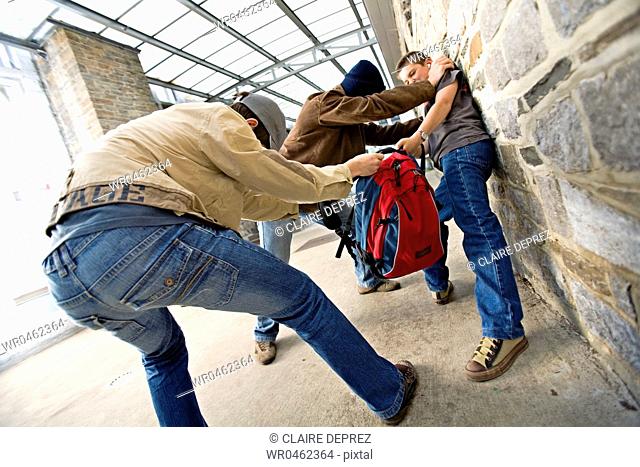 Two teenage boys snatching a bag from a teenage boy