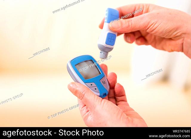 Woman with adult onset diabetes measuring blood sugar with indicator