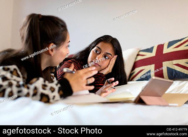 Teenage girls studying, talking on bed