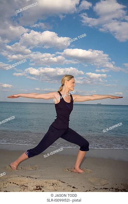 Mid adult woman in yoga pose on beach