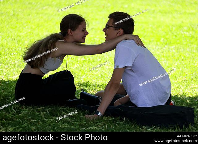 RUSSIA, MOSCOW - JULY 4, 2023: A couple sits on the grass in Alexander Garden. Mikhail Metzel/TASS