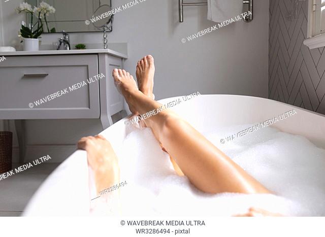 Close-up of woman lying in the bathtub with her legs crossed