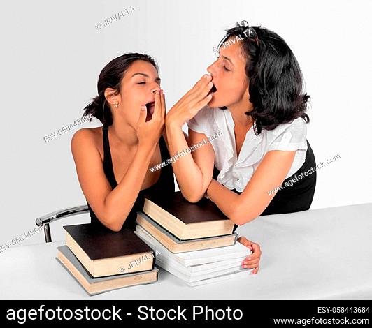 A girl sitting and a woman stand with books both yawning