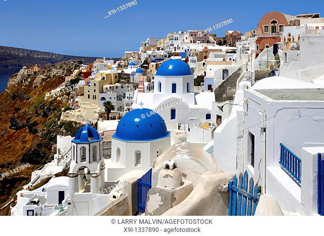 Cliffside view of buildings and blue domes in the village of Oia in Santorini, Greece