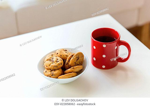 christmas, holidays, winter, celebration and still life concept - close up of oat cookies and red tea cup on table at home