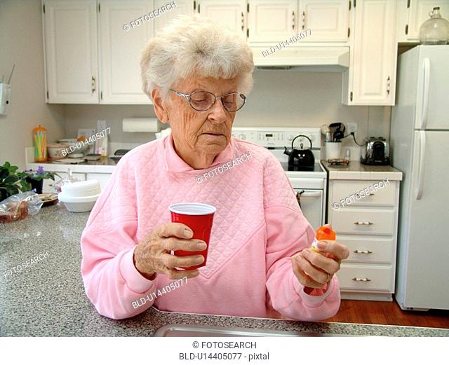 An elderly woman takes her daily prescriptions