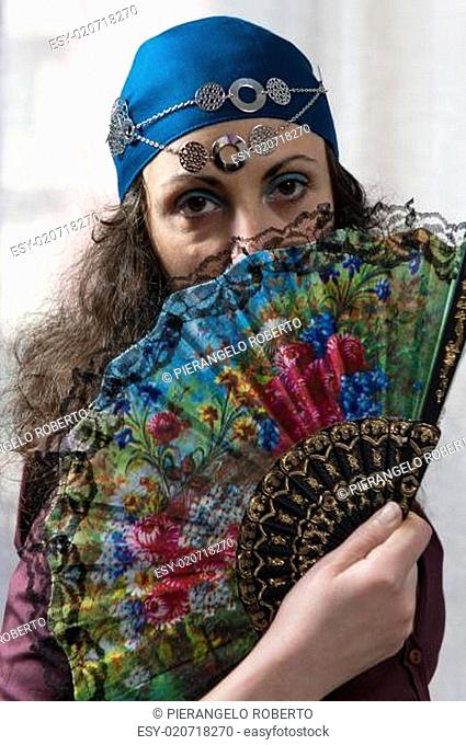 young woman hiding her face behind a fan colored