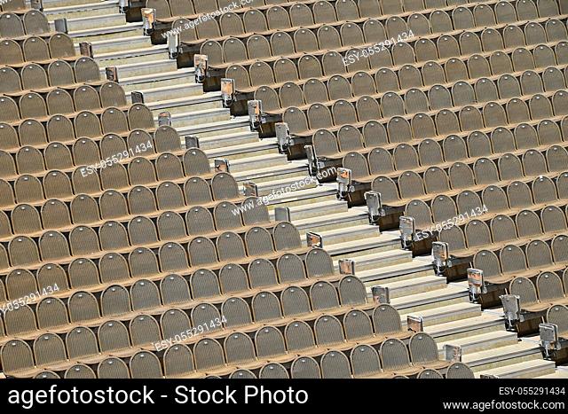 Rows of empty grey and red seats in open air concert hall auditorium, high angle side view