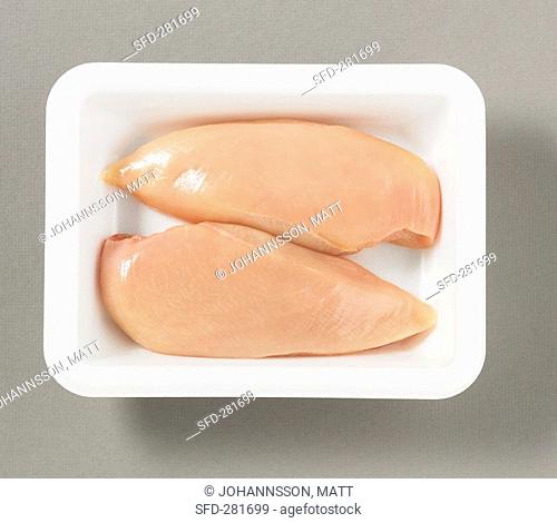 Two chicken breast fillets on plastic tray