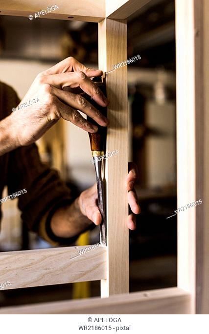 Cropped image of carpenter's hands using chisel in workshop