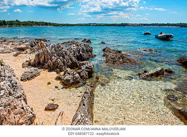 Pathway on the beautiful rocky beach in Istria, Croatian coast. Blue sea, sky and island on horizon