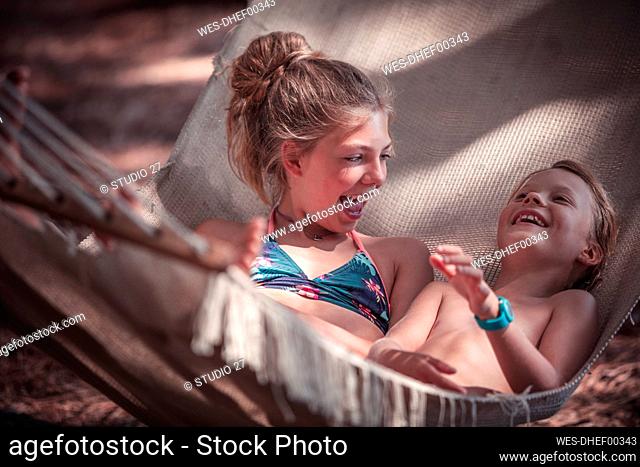 Happy girls relaxing on hammock at beach during summer