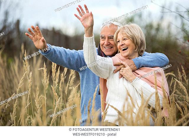 Portrait of happy senior couple having a walk and greeting someone