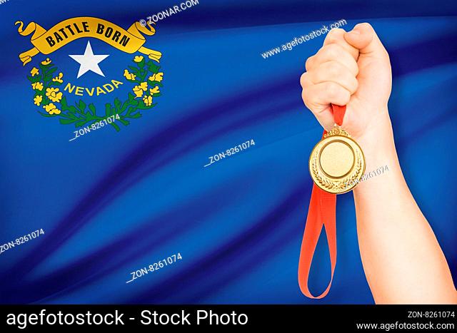 Sportsman holding gold medal with State of Nevada flag on background. Part of a series