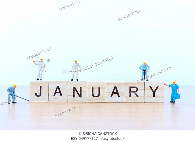 January words with Miniature people worker on wooden floor