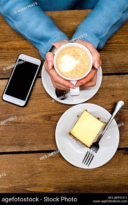 Woman with froth art on coffee at table