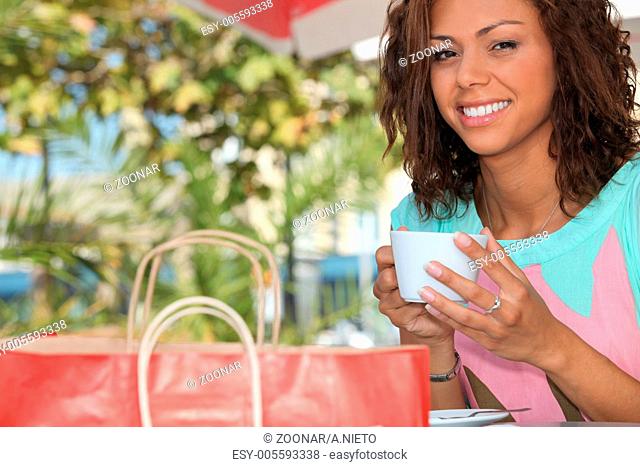 Woman with a shopping bag drinking tea outside
