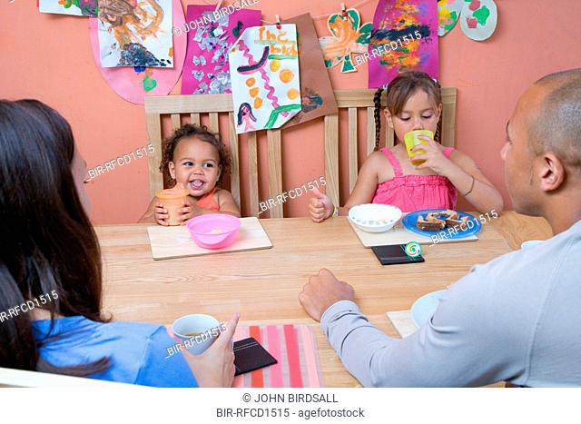 Young family sitting around the dinner table eating a snack