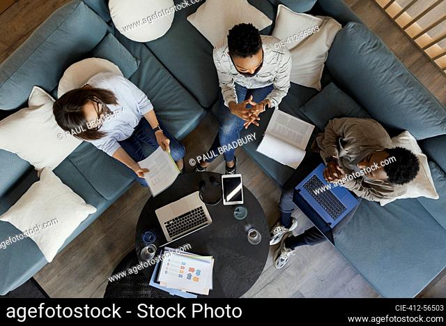 Business people with laptops and paperwork meeting on office sofa