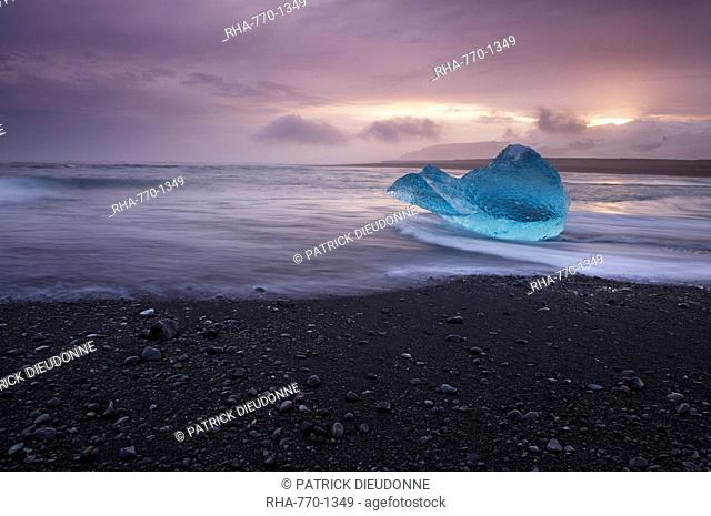 Translucent blue iceberg washed ashore on Breidamerkursandur black sands, near Jokulsarlon glacial lagoon, East Iceland, Iceland, Polar Regions