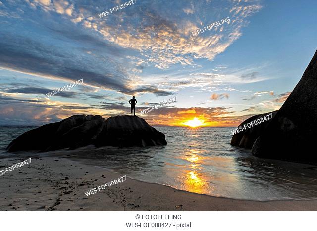 Seychelles, La Digue, beach, man standing on granite rock at sunset
