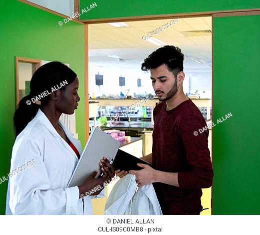Young female and male scientists in laboratory doorway