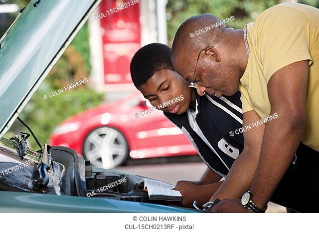 father & son working on car engine