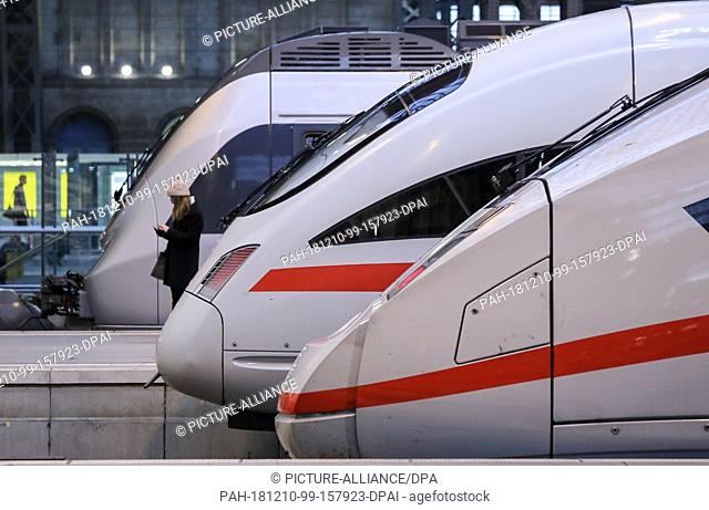 10 December 2018, Saxony, Leipzig: A passenger waits between two ICE long-distance trains and a regional train on a platform at Leipzig Central Station