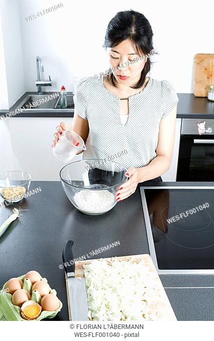 Woman pouring water in a glassbowl of flour