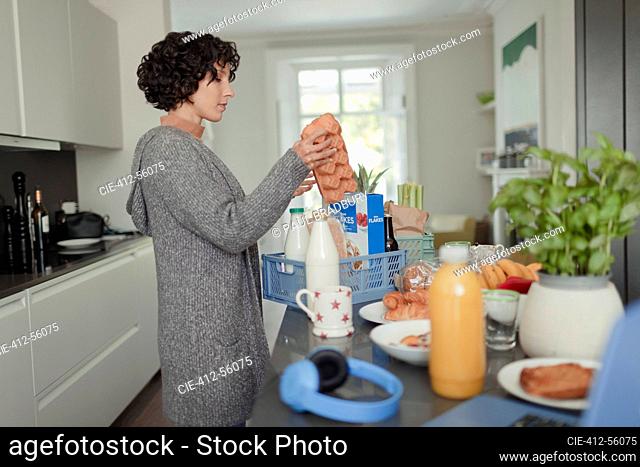 Woman unloading grocery delivery at kitchen counter