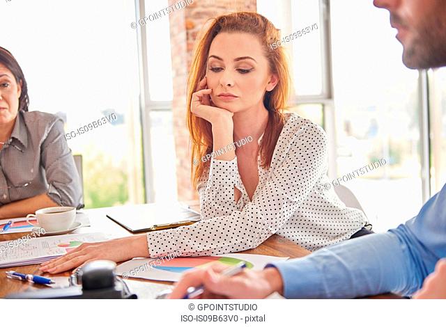Businesswoman in meeting hand on chin looking pensive