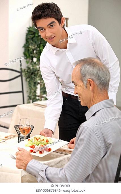 Young waiter serving an older customer
