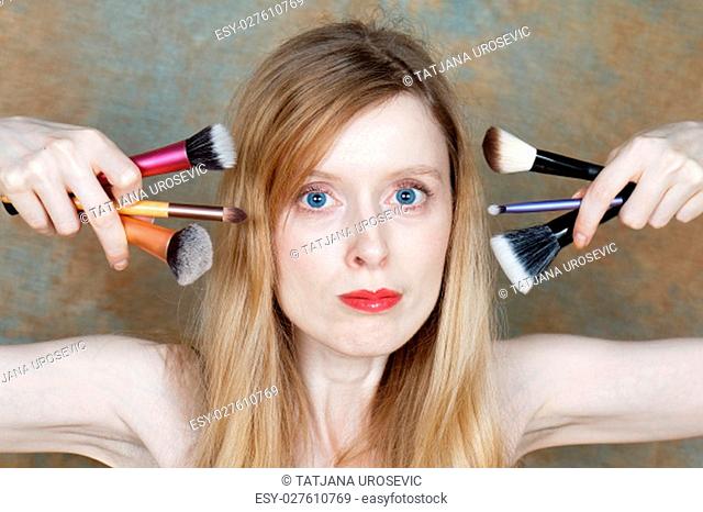 Young woman holding make up brushes close to her face