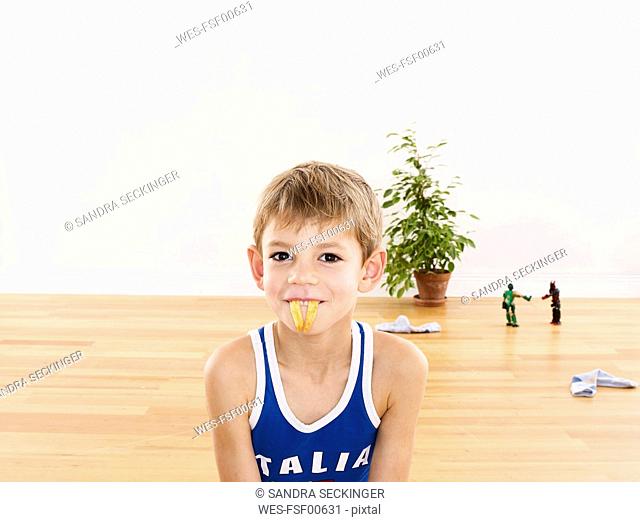Portrait of little boy holding French fries with his mouth