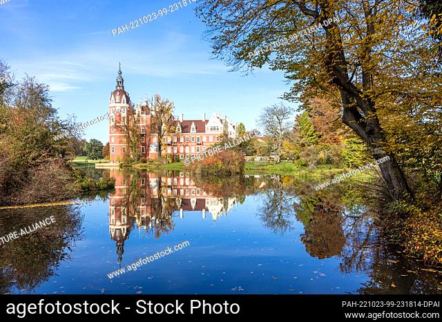 23 October 2022, Saxony, Bad Muskau: The New Palace in Fürst Pückler Park is reflected in a pond in the sunshine. The approximately 800-hectare English-style...
