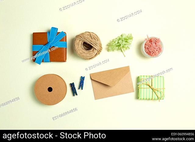 Gift boxes, ribbon string, wooden clip, envelope, dry flowers on yellow green background. flat lay, top view, copy space