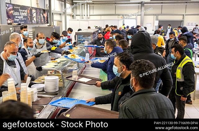 PRODUCTION - 16 November 2022, Baden-Wuerttemberg, Ellwangen: Refugees are crowding the food counter at the state's initial reception center (LEA)
