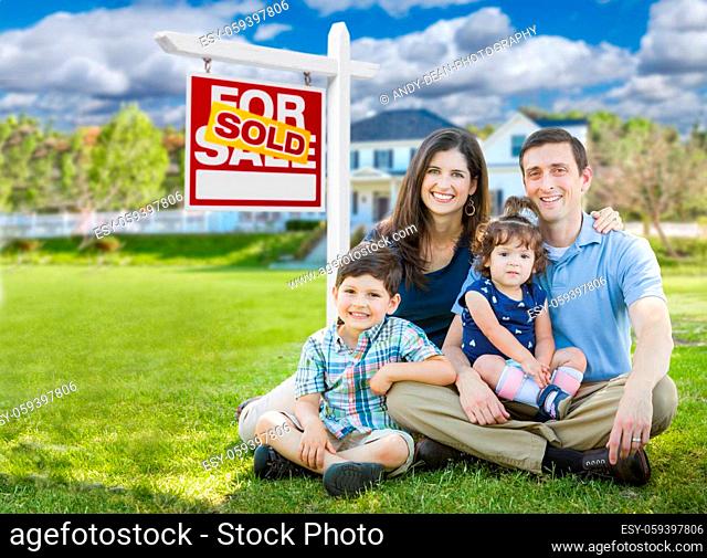 Young Family With Children In Front of Custom Home and Sold For Sale Real Estate Sign