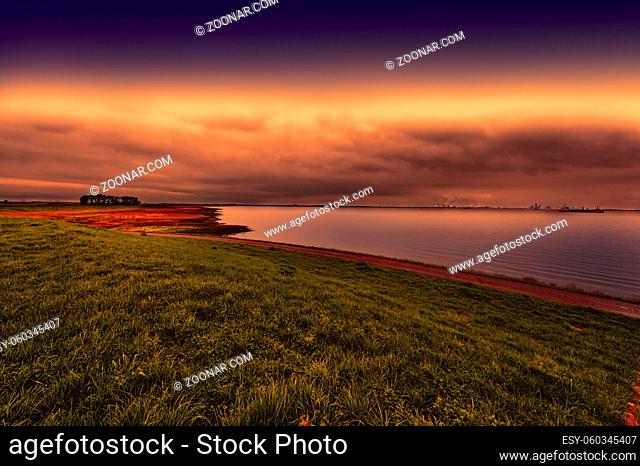 Dunes and sea at the North Sea shore in Holland at sunset. Dutch landscape with dike protects against flooding