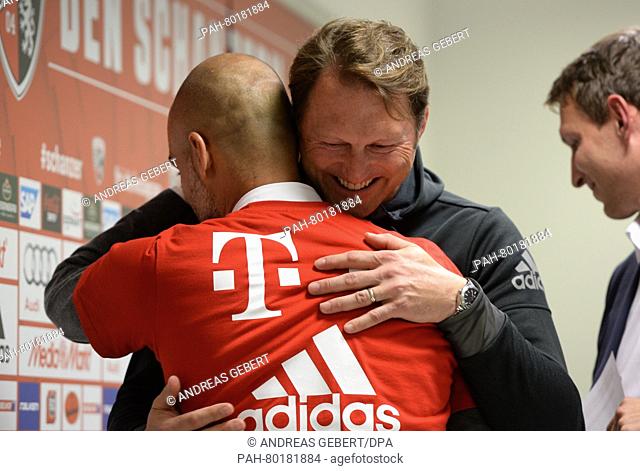 Ingolstadt's head coach Ralph Hasenhuettl (back) embraces his Munich counterpart Pep Guardiola (front) after the press conference held after the German...