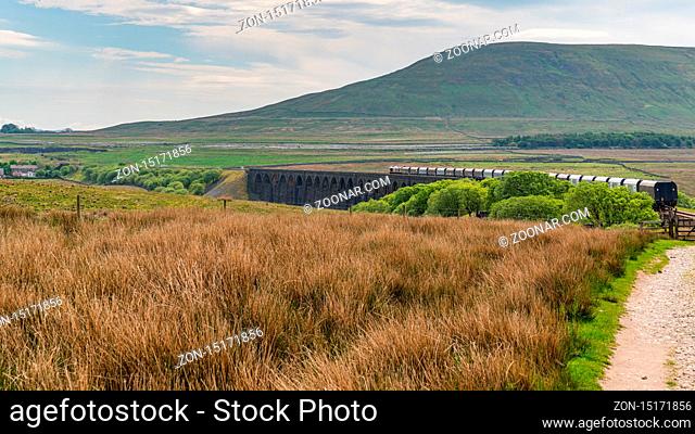 Near Ribblehead, North Yorkshire, England, UK - May 17, 2019: A freight train passing the Ribblehead Viaduct
