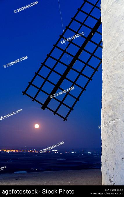 abstract detail view of a whitewashed windmill and wooden blade just after sunset with a full moon on the rise