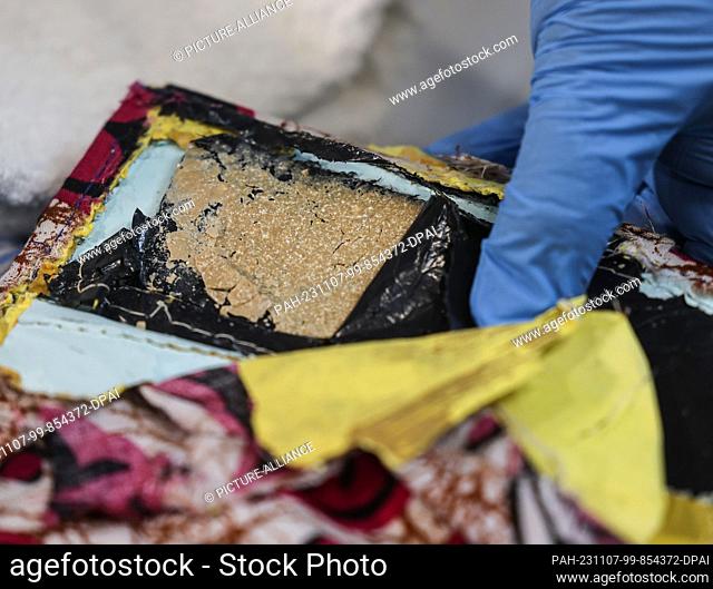 07 November 2023, North Rhine-Westphalia, Cologne: An employee of the main customs office in Cologne shows a stash of heroin sewn into a cloth bag