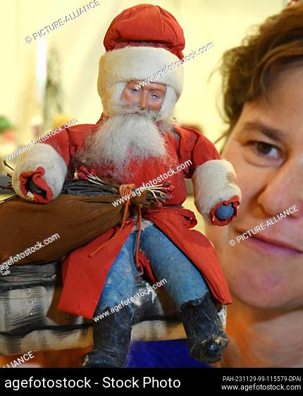 PRODUCTION - 21 November 2023, Saxony, Oschatz: In a special exhibition at the City and Scales Museum, director Dana Bach is holding an almost 80-year-old Santa...