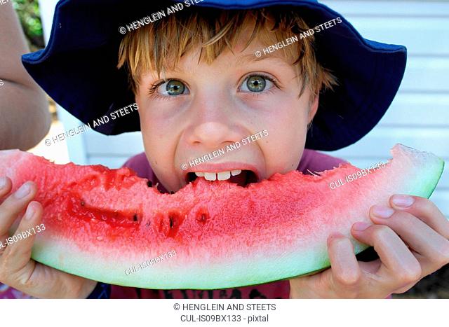 Boy biting into watermelon